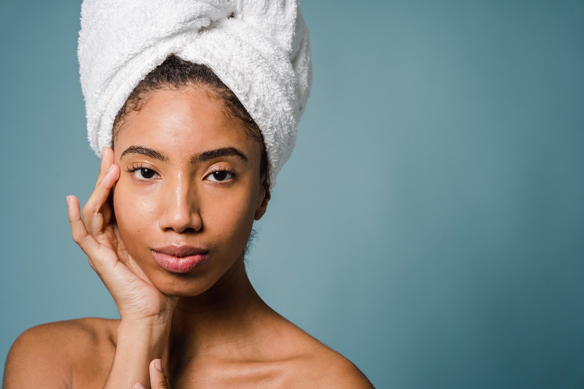 woman wearing towel in hair and touching face